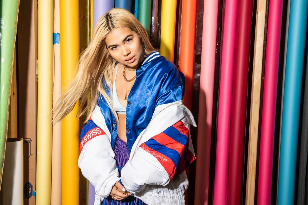 Hayley Kiyoko posing in front of a colorful wall.