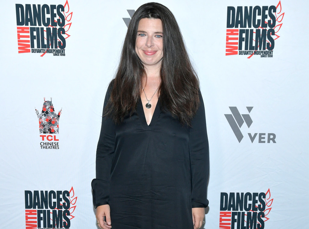 Heather Matarazzo posing in a red carpet, wearing her long brown hair down, and dawning a black dress.