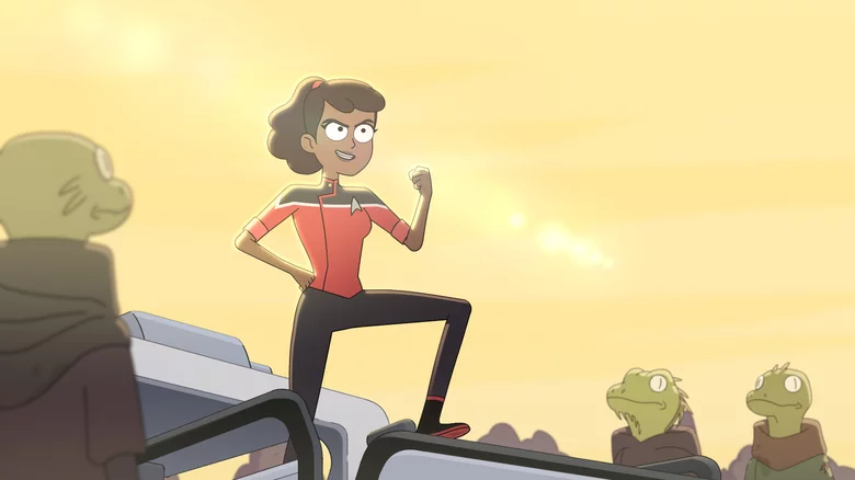 A woman from Starfleet is standing victoriously with her knee up and her fist held up in the air.