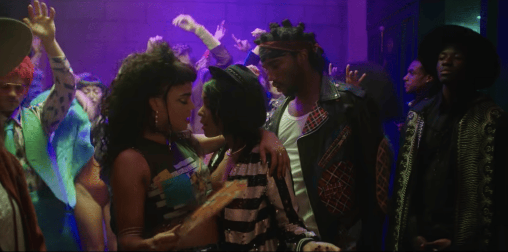 Janelle Monáe dances between a man and a woman (Tessa Thompson)