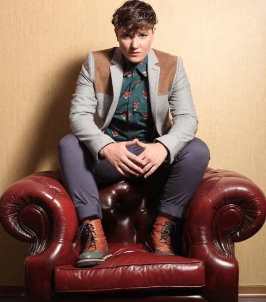 Handsome androsexual queer posing and being sexy on a red leather couch