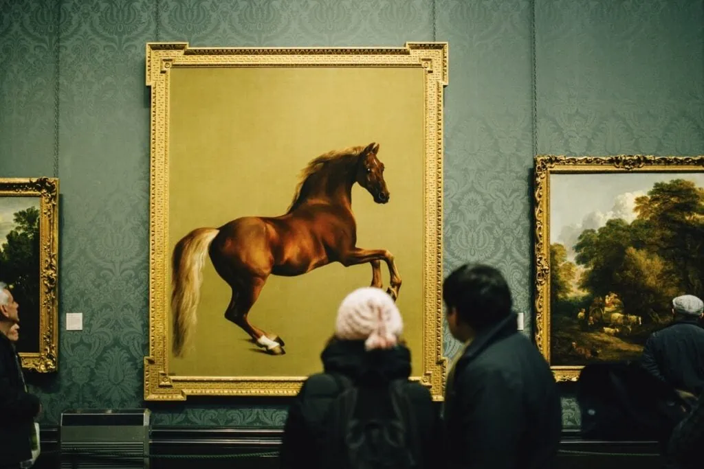 A couple admire a piece of art hanging on a wall in a museum