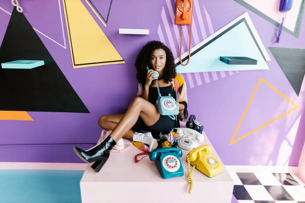 A stylish femme woman sits wearing boots and a black two-piece.