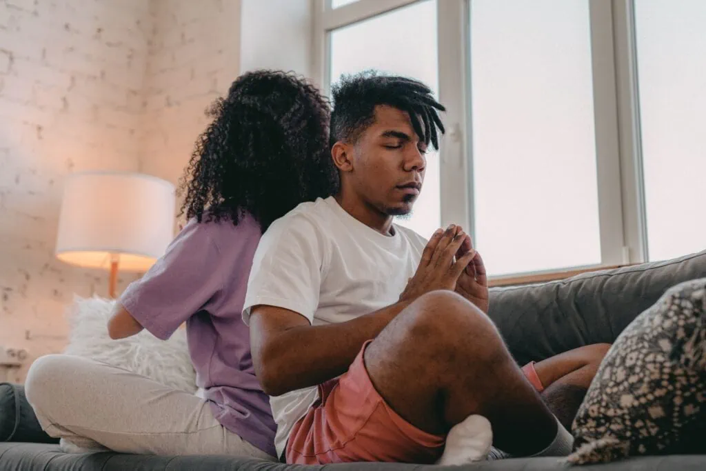 A couple practice yoga together in a living room