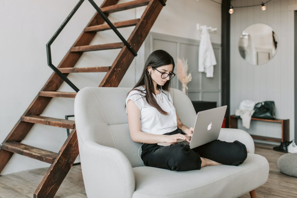 Focused woman using earphones and laptop at home during work