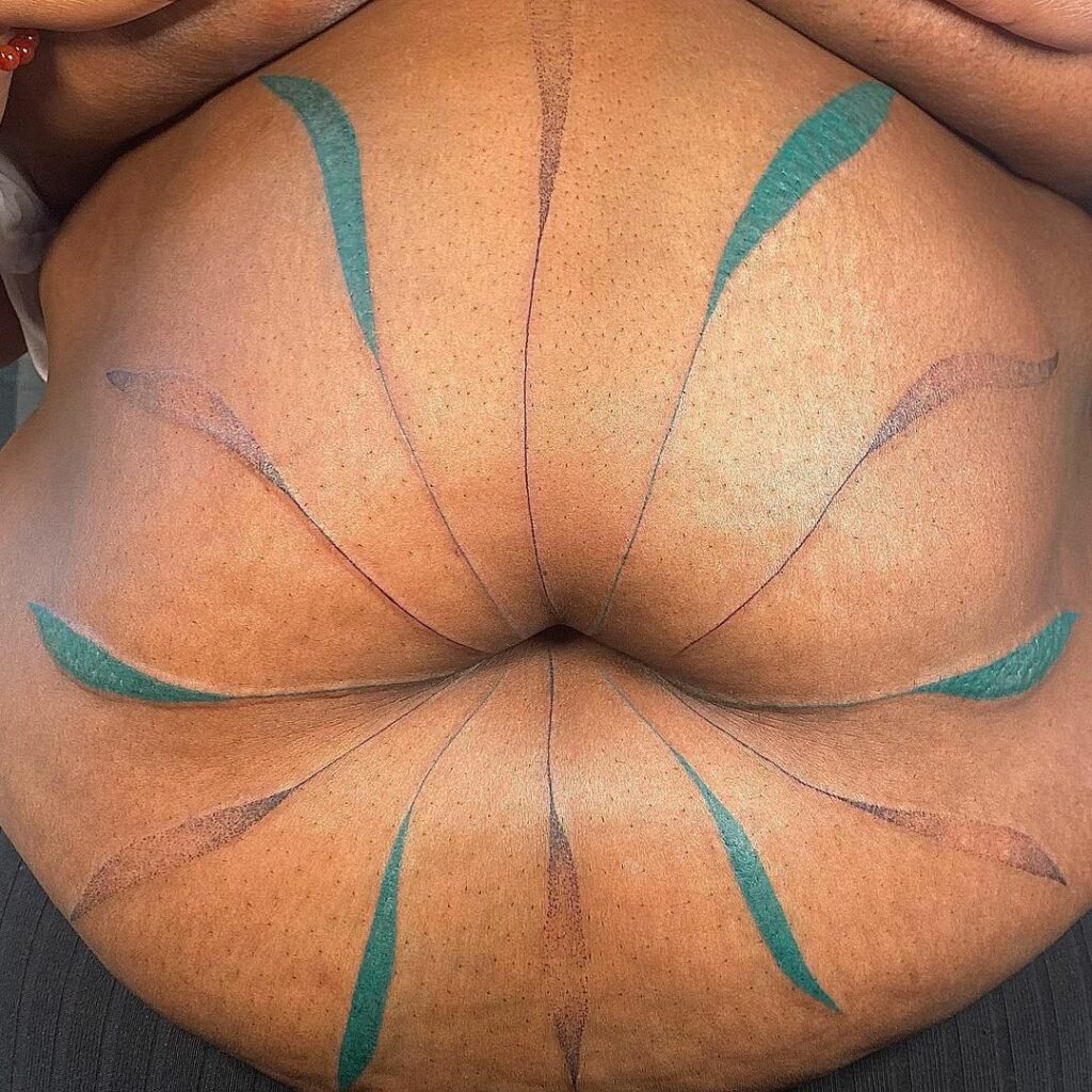 A simple LGBT tattoo of leaves extending from a large black belly by Tiaret Renee