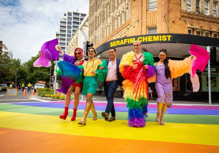 Cute queer folks prancing across a rainbow street crossing in Sydney’s Oxford Street district