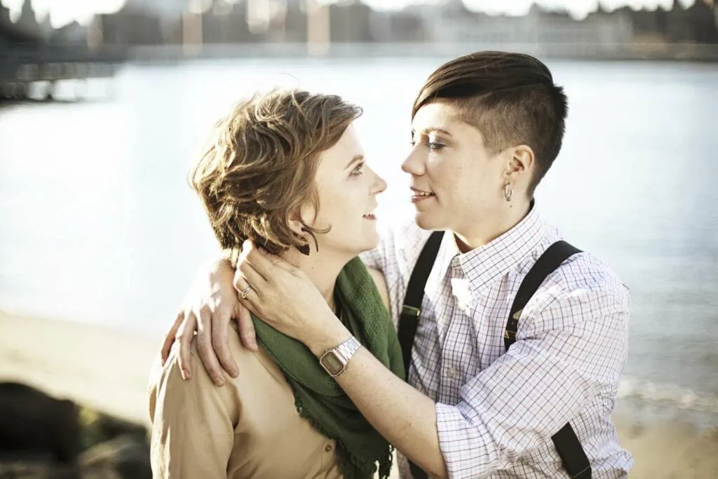 Butch-femme queer love in a lakeside embrace
