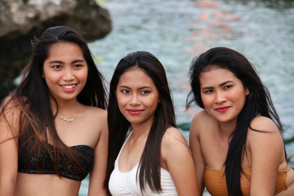Three young femme lesbians smiling and hanging out beside a body of water near Manila
