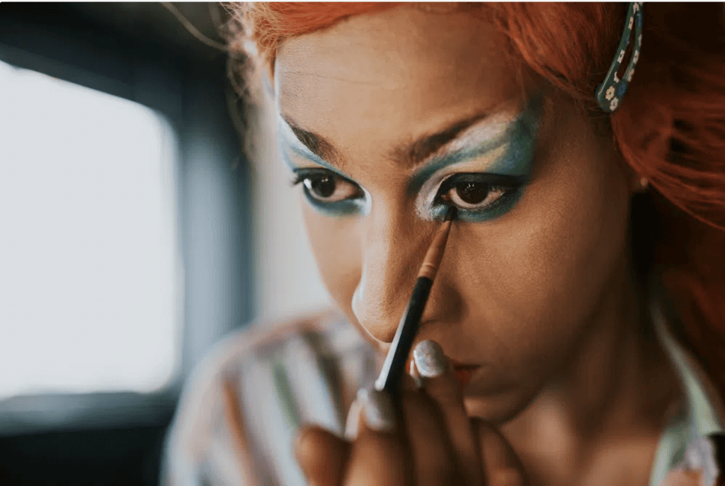 A demigirl, someone whose identity is not entirely aligned with womanhood, applies colorful makeup.