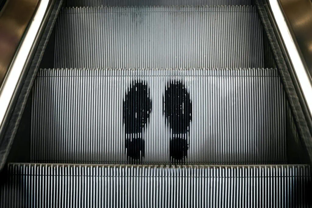 A picture of an escalator with an outline of two shoes, to represent the concept of ‘getting off the relationship escalator’ that is popular in solo polyamory.