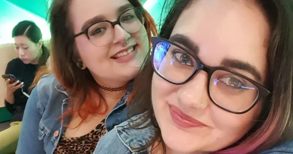 Lesbian dopplebanger couple posing for a selfie with a neon green background