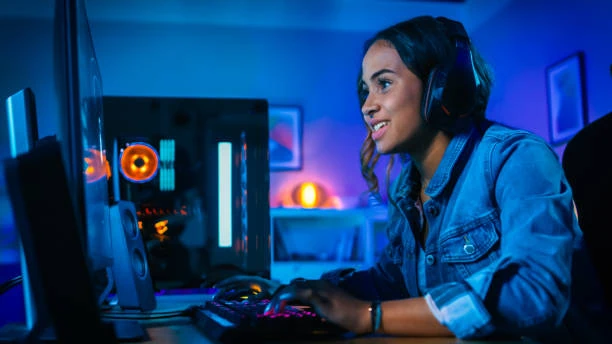 Girl playing on a gaming PC, she is wearing a headset and looks happy. Blue background and lightning are predominant.