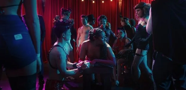 A still from ‘Lust, Life, Love’ is a movie about a bisexual polyamorist named Veronica, played by Stephanie Sellars. This scene is a play party with diverse people gathered around. 