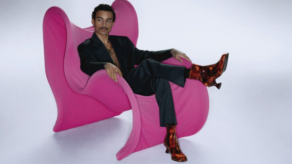 Reece King posing in a pink, odd-shaped chair.