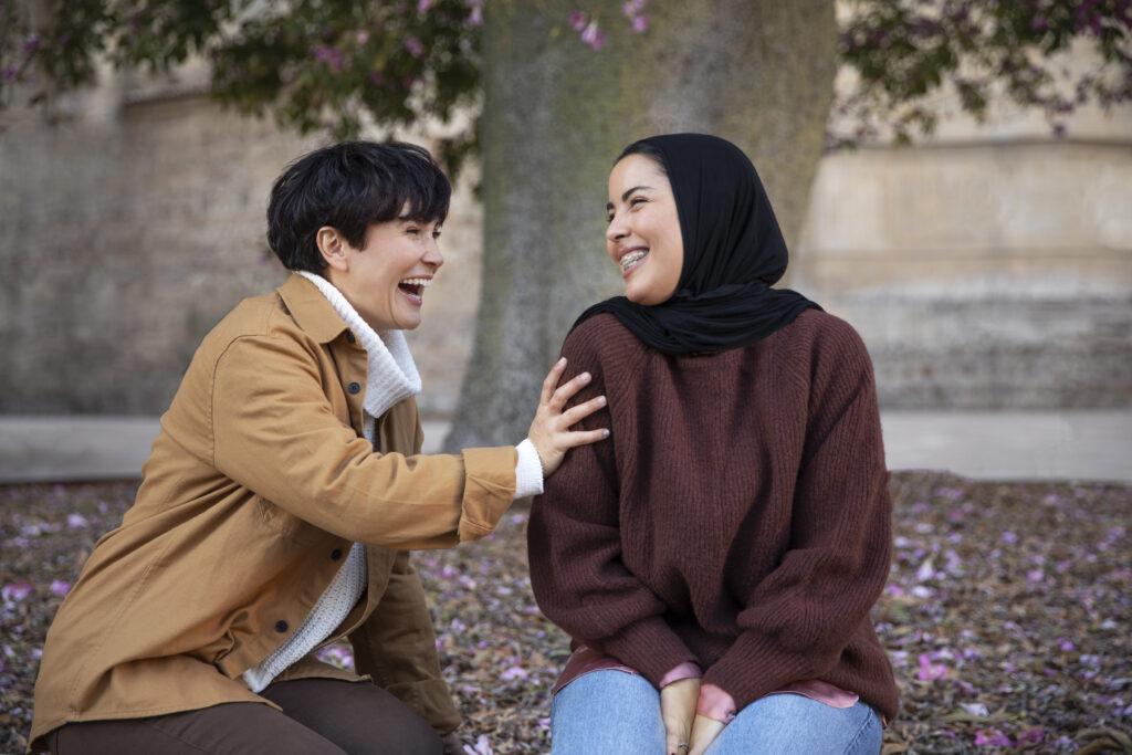 Happy people chatting and laughing by a tree.