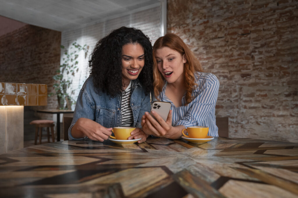 Two women looking at the same phone with excitement.