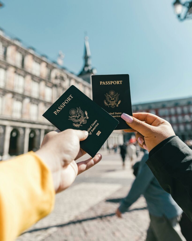 Two queer American tourists holding up their US passports on a sunny day in France.