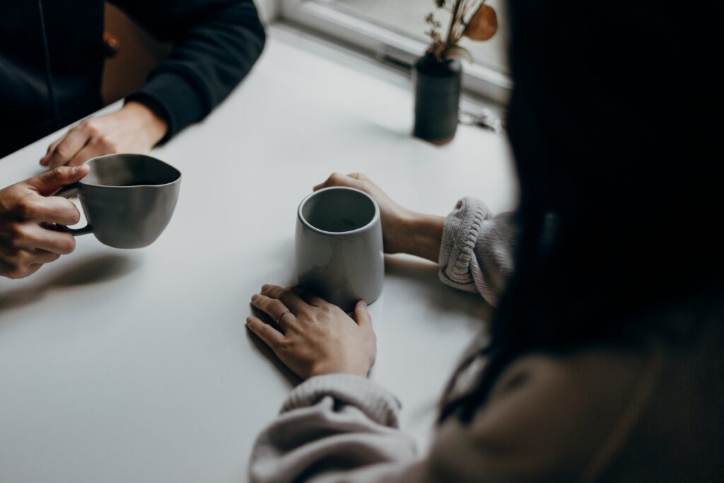 A lesbian couple discuss their dating goals over cups of coffee. 