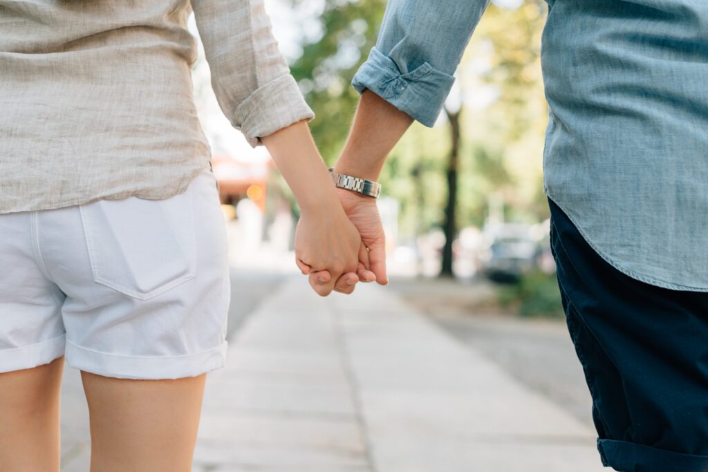 A lesbian couple with ADHD hold hands on a sidewalk.