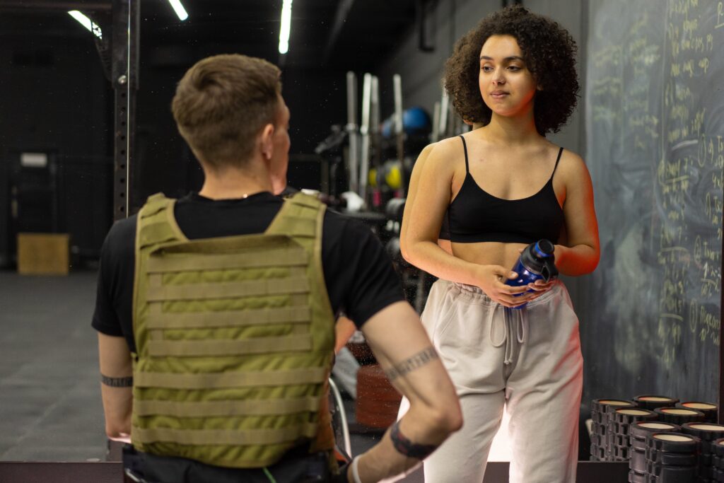 a woman standing confidently in an LGBT gym and wellness space in New York City. The background showcases exclusive features of queer-friendly gyms.