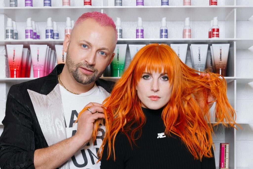 Photo of Hayley Williams, founder of Nashville Fruits Hair Lab, an LGBT-safe salon, standing beside her colleague. Hayley displays her stunning, colorful hair, symbolizing the salon's commitment to creativity, inclusivity, and artistic expression.