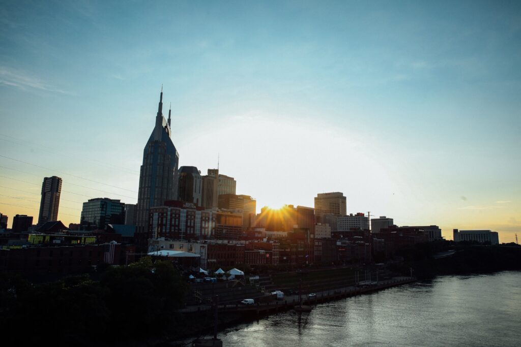 An early morning view in Nashville, Tennessee, showcasing the serene landscape bathed in the warm, golden hues of sunrise. The skyline is gently illuminated, with the rising sun casting a soft glow over the city's distinctive architecture and surrounding natural beauty.