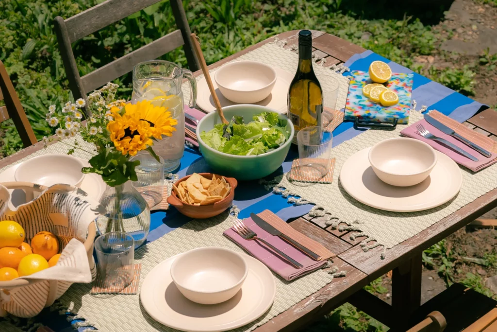 Outdoor dining table with plates, fruit and salad.