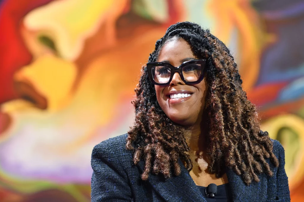 Thasunda Brown Duckett smiling over a colorful background.