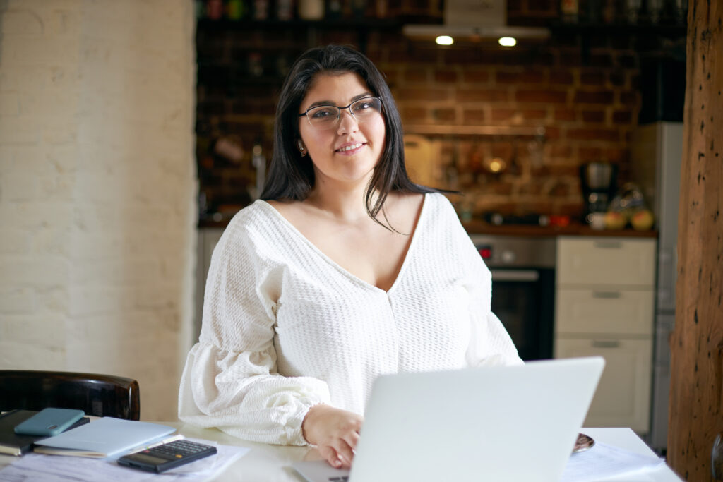 Woman with her laptop smiling at camera.