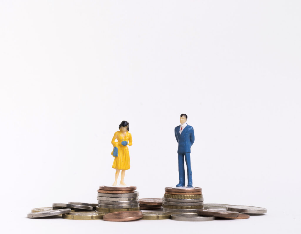 Business woman and man figurines standing on coins.