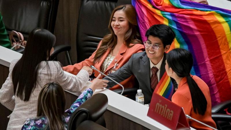Joyful Move Forward party member celebrating the passage of the Equal Marriage Act in The House of Representatives, with a bright smile and happiness.