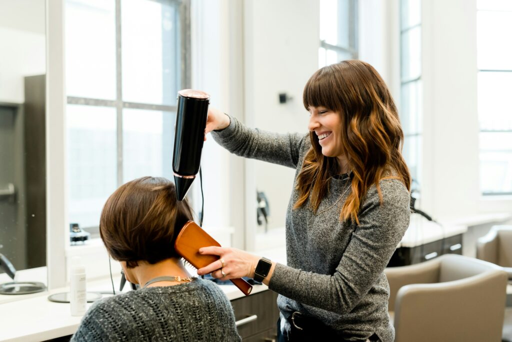 A lesbian hair stylist drying the hair of a queer customer in a welcoming and inclusive LGBTQIA+ salon