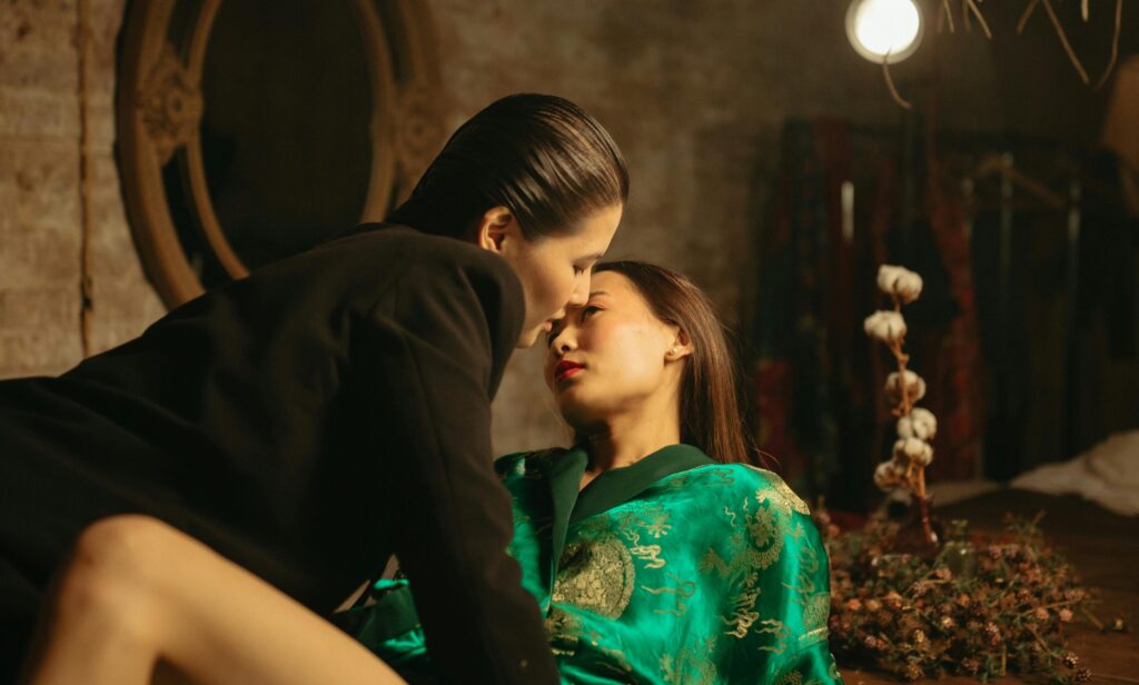 Two women on a romantic date lying on a dining table together under a soft, romantic light
