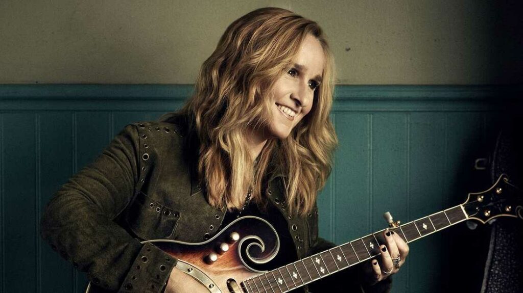 Melissa Etheridge, a singer-songwriter, playing guitar with a big smile