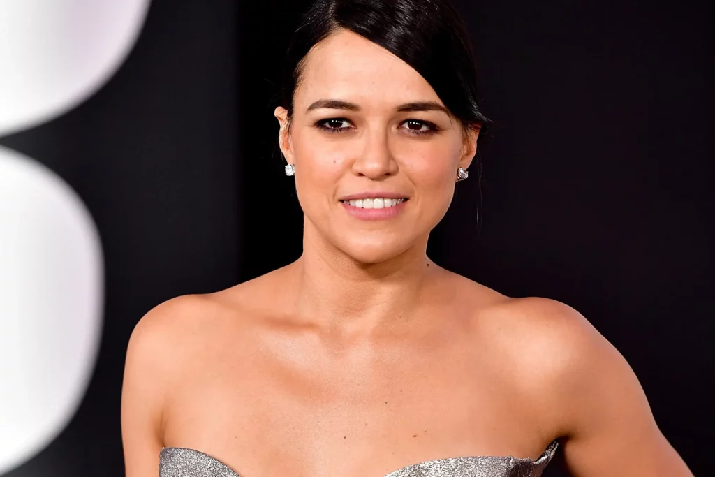 Photo of Michelle Rodriguez at an event. She is smiling and wearing an elegant dress.
