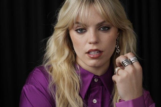 Photo of Reneé Rapp, exuding confidence. Her hands are covered in a variety of rings.