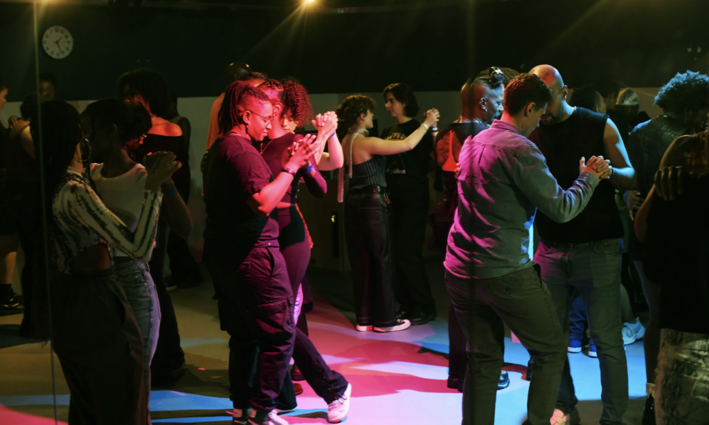 Image of a lively dance floor at the Common Press, filled with diverse members of the queer community enjoying a vibrant event