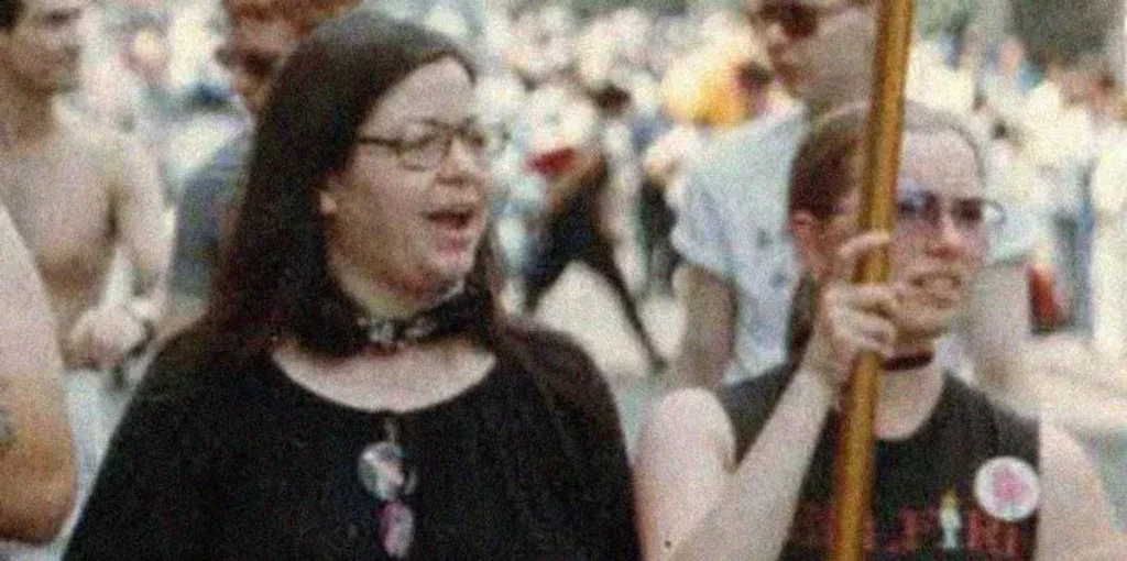Brenda Howard, a key figure in the LGBTQ+ rights movement known as the 'Mother of Pride,' standing on a street protesting, surrounded by fellow activists.