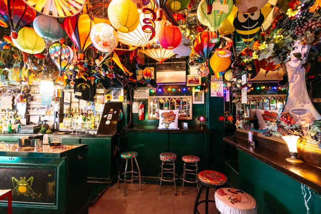 Interior of Cubbyhole bar adorned with vibrant balloon-style lights. The walls are painted in dark green, contrasting with the brown brick colored floor.
