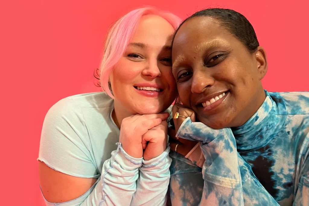 Close-up photo of Nikke Alleyne and Justine LaViolette, co-owners of The Bush, sitting and smiling in front of a pink background.