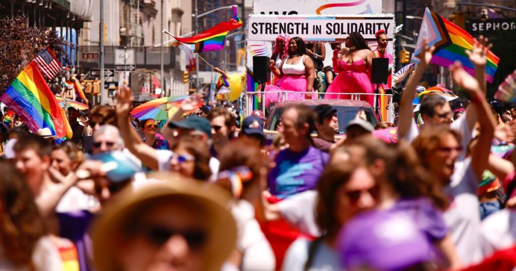 A vibrant crowd celebrates at The 53rd Annual Pride March, with people joyously waving rainbow flags.