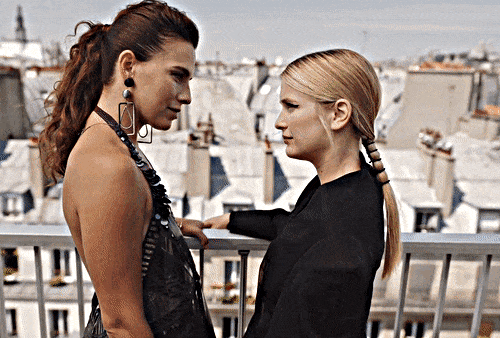 Camille and Sofia, characters from the series 'Emily in Paris,' sharing a romantic kiss.