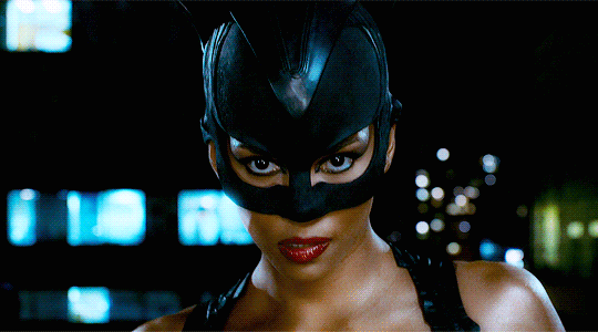 Halle Berry as Catwoman struts confidently toward the camera with her black leather costume.
