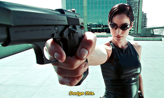 Trinity from 'The Matrix' holding a gun and saying 'Dodge this'