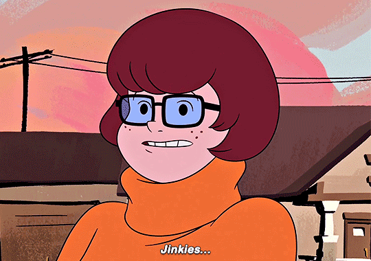 Velma Dinkley from Scooby-Doo, blushing and looking shy, as she gazes lovingly at another woman cartoon character, hinting that she might be falling in love.