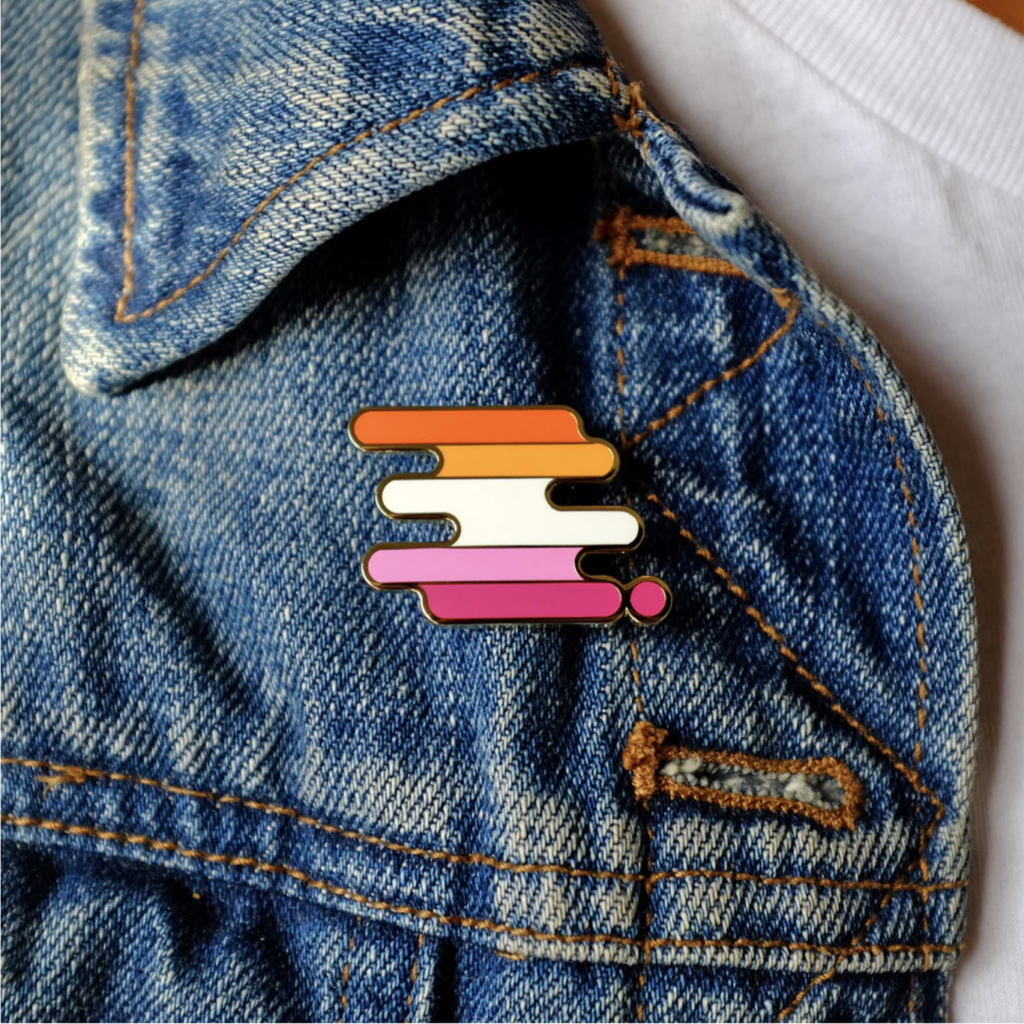 Close-up of an enamel pin in lesbian flag colors pinned on a denim jacket—a perfect example of lesbian pride accessories for everyday wear.